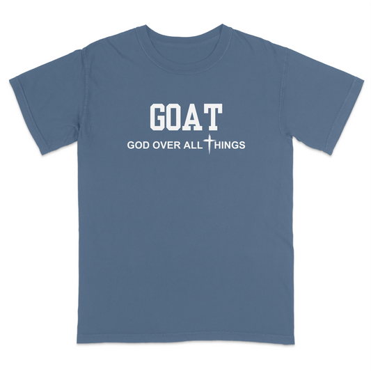 Blue jean faith-based Christian t-shirt featuring the bold word “GOAT” across the chest with the phrase “God Over All Things” underneath and a white cross graphic. Inspirational religious apparel designed for believers, church events, youth groups, Christian streetwear, Bible study gatherings, and everyday faith-centered fashion.