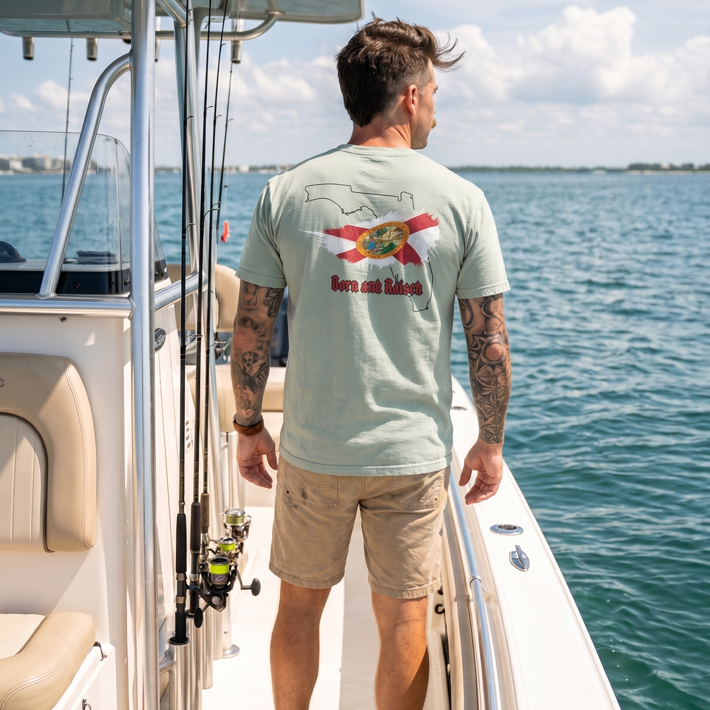 Man wearing a Florida Born and Raised graphic T-shirt on a fishing boat, featuring a Florida state outline and Florida flag design. Coastal Florida lifestyle apparel perfect for boating, fishing, and outdoor adventures.
