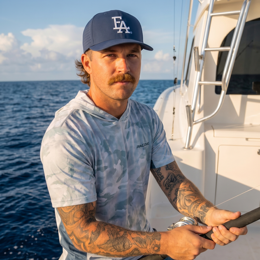Man wearing a blue FLA® performance snapback hat with white embroidered logo while fishing offshore. Lightweight structured cap designed for boating, fishing, and outdoor Florida adventures on the water.