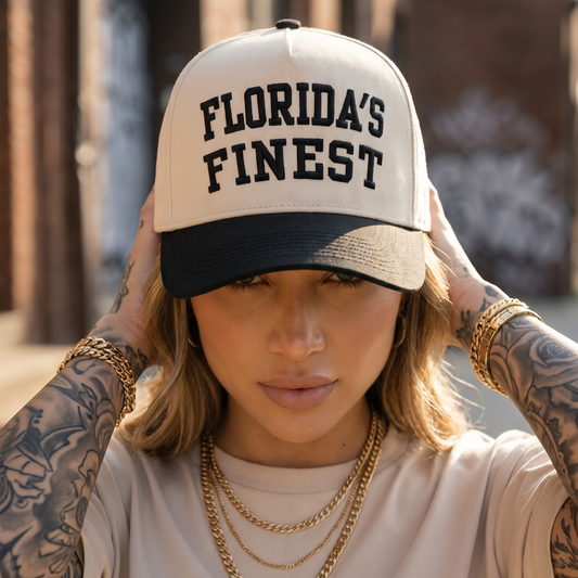Close-up lifestyle photo of a woman wearing a cream and black Florida’s Finest embroidered snapback hat.