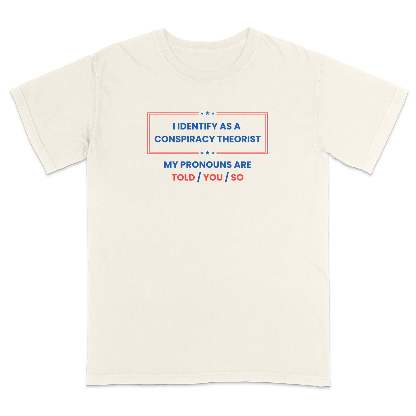 Front view of a ivory graphic T-shirt featuring the humorous phrase "I Identify as a Conspiracy Theorist" with "My Pronouns Are Told / You / So" printed below in bold patriotic red and blue lettering with stars and a bordered design. A funny political humor tee perfect for casual wear, parties, holidays, and anyone who enjoys satire and conspiracy-themed jokes.