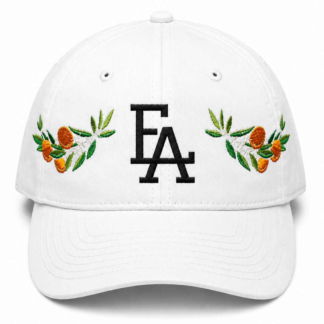 White baseball cap featuring a white embroidered “FLA” logo on the front, accented with colorful citrus and floral embroidery on both sides for a Florida-inspired design.