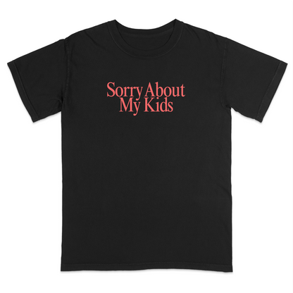 Front view of a black graphic T-shirt featuring the phrase "Sorry About My Kids" in large soft pink serif lettering centered across the chest. This minimalist parenting humor tee offers a clean modern design, making it perfect for moms, dads, school events, family outings, playdates, and everyday casual wear.