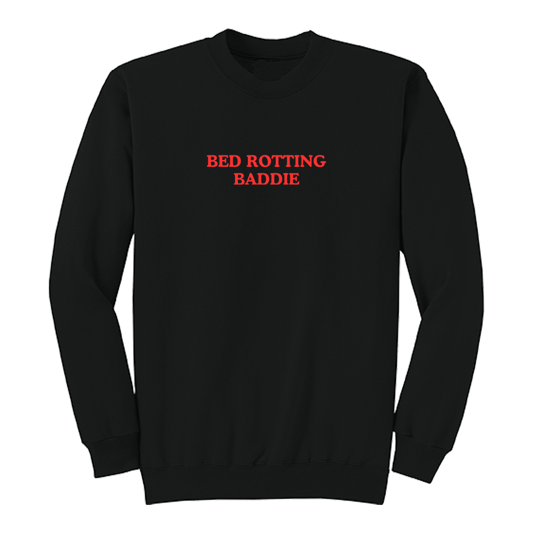 Front view of a black crewneck sweatshirt featuring the phrase "BED ROTTING BADDIE" in small vintage-style red lettering centered on the chest. This minimalist graphic sweatshirt combines cozy comfort with trendy Gen Z-inspired humor, making it perfect for lounging, casual outings, and everyday wear.