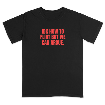 Front view of a black graphic T-shirt featuring the bold red statement "IDK HOW TO FLIRT BUT WE CAN ARGUE." centered across the chest in large uppercase block lettering. This funny sarcastic T-shirt combines relationship humor with bold typography, making it a casual streetwear design for adults with a playful sense of humor.
