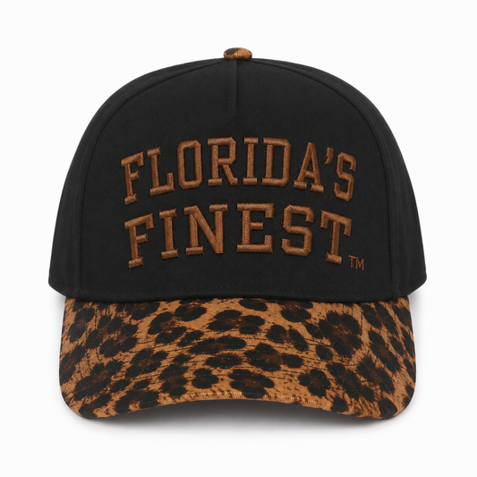 Front view of a black snapback hat featuring bold brown embroidered "Florida's Finest™" lettering across the crown. The hat has a brown leopard print curved brim, matching leopard print top button, and premium raised embroidery, blending classic black with a bold animal print accent for a stylish streetwear look.