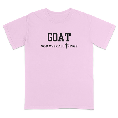 Pink faith-based Christian t-shirt featuring the bold word “GOAT” across the chest with the phrase “God Over All Things” underneath and a white cross graphic. Inspirational religious apparel designed for believers, church events, youth groups, Christian streetwear, Bible study gatherings, and everyday faith-centered fashion.