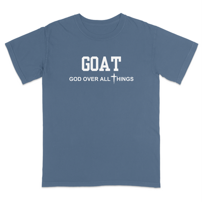 Blue jean faith-based Christian t-shirt featuring the bold word “GOAT” across the chest with the phrase “God Over All Things” underneath and a white cross graphic. Inspirational religious apparel designed for believers, church events, youth groups, Christian streetwear, Bible study gatherings, and everyday faith-centered fashion.