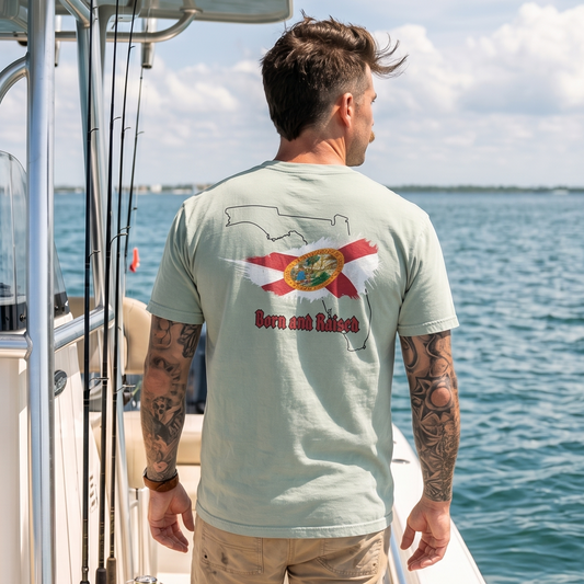 Man wearing a Florida Born and Raised graphic T-shirt on a fishing boat, featuring a Florida state outline and Florida flag design. Coastal Florida lifestyle apparel perfect for boating, fishing, and outdoor adventures.