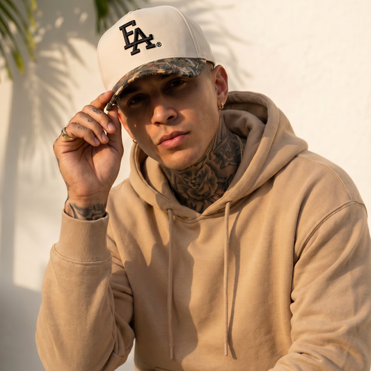 Lifestyle photo of a model wearing a white and camo brim FLA® baseball cap with black embroidered logo. Premium curved-brim hat styled with a neutral hoodie, showcasing modern Florida-inspired streetwear fashion.