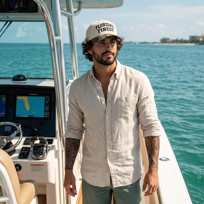 Man wearing a Florida’s Finest embroidered snapback hat with a cream crown and camo-pattern brim while boating on clear Florida waters. Coastal lifestyle cap designed for fishing, boating, outdoor adventures, and Florida-inspired everyday style.