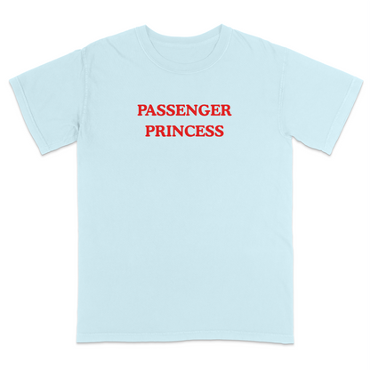 Front view of a light blue graphic T-shirt featuring the phrase "PASSENGER PRINCESS" in bold red vintage-style lettering centered across the chest. This minimalist graphic tee offers a playful automotive-inspired design, making it perfect for road trips, date nights, vacations, casual outings, and everyday wear.