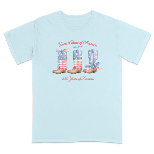 Chambray patriotic graphic tee featuring vintage American flag cowboy boots with “United States of America,” “Est. 1776,” and “250 Years of Freedom” text for a western-inspired Americana look.