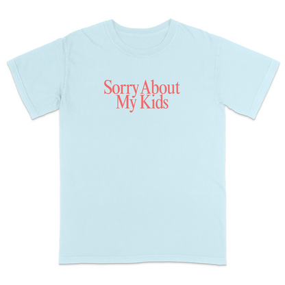 Front view of a light blue graphic T-shirt featuring the phrase "Sorry About My Kids" in large soft pink serif lettering centered across the chest. This minimalist parenting humor tee offers a clean modern design, making it perfect for moms, dads, school events, family outings, playdates, and everyday casual wear.