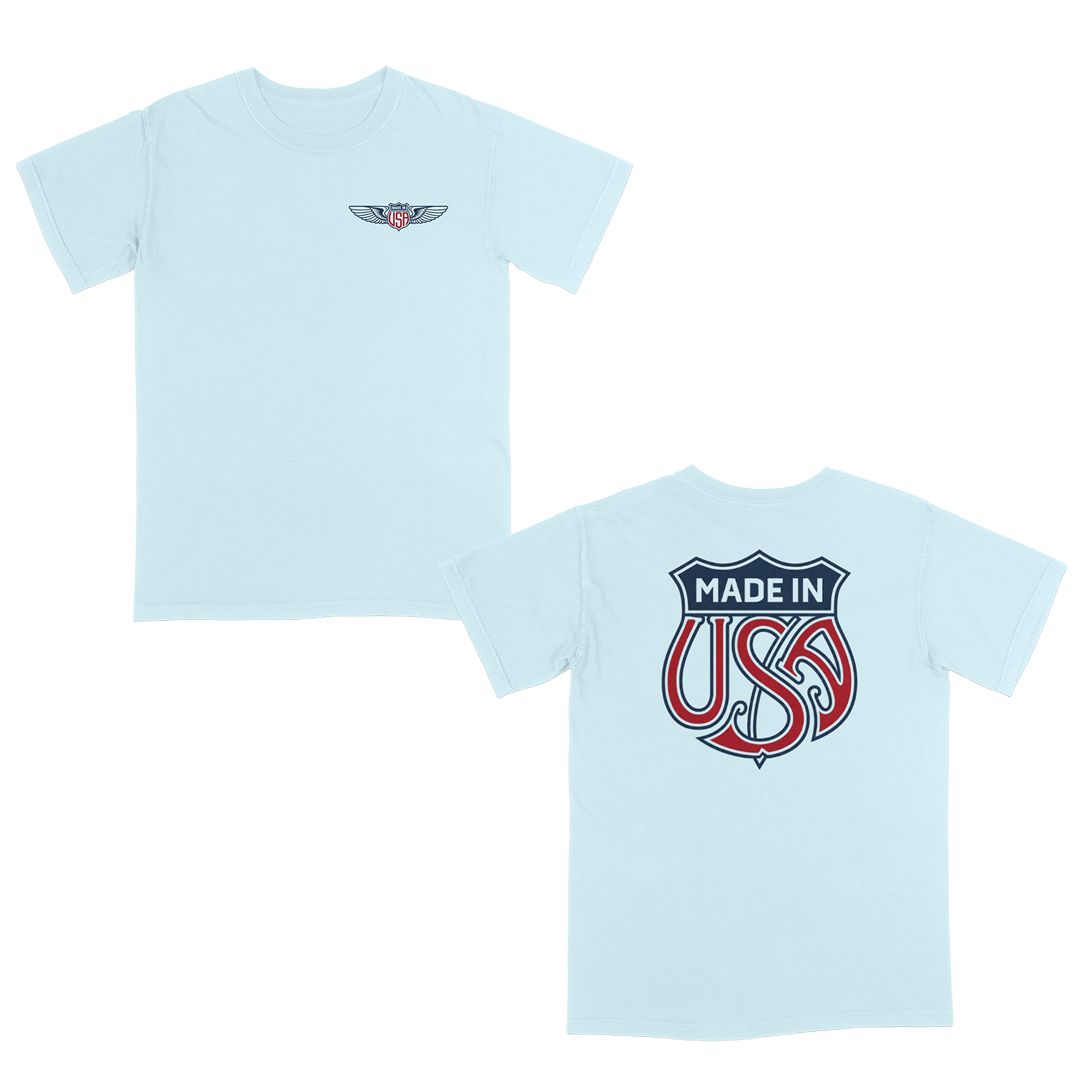 Light blue patriotic graphic t-shirt with small USA wing logo on the front and oversized “Made in USA” graphic on the back in vintage red and blue Americana style.