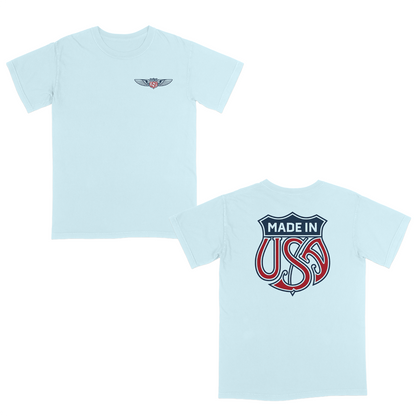 Light blue patriotic graphic t-shirt with small USA wing logo on the front and oversized “Made in USA” graphic on the back in vintage red and blue Americana style.
