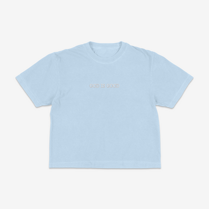 Light blue boxy tee with 'GOD IS GOOD' text on a white background