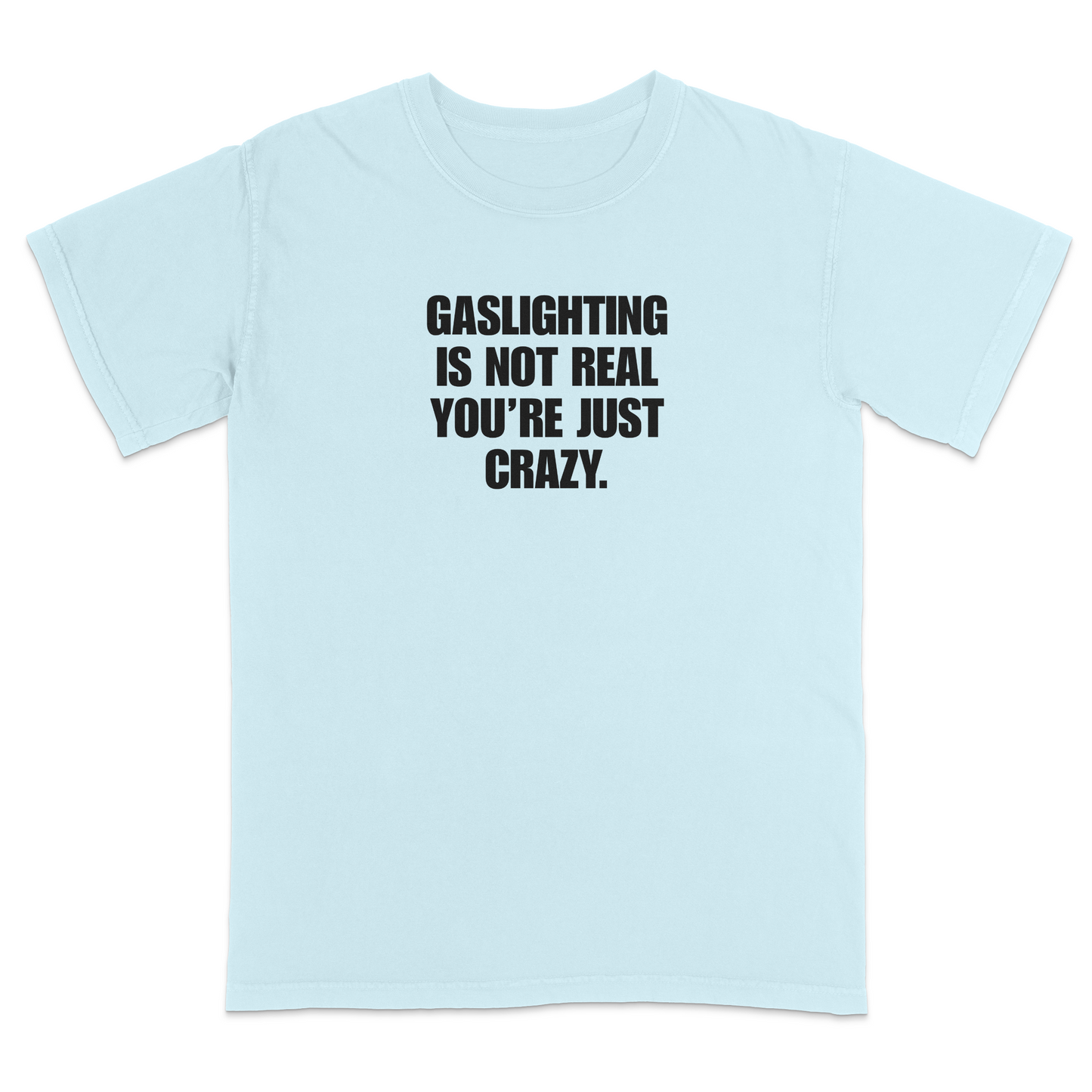 Front view of a chambray short sleeve t-shirt featuring the phrase "GASLIGHTING IS NOT REAL YOU’RE JUST CRAZY." printed in bold black uppercase lettering centered on the chest. The high-contrast black-and-white design creates a clean, minimalist statement tee with a humorous, sarcastic style.