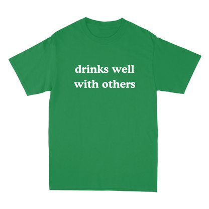 Green t-shirt with 'drinks well with others' text on a white background