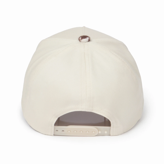 Back view of a cream snapback hat featuring a brown and cream cow print top button and an adjustable cream snapback closure. Displayed on a white background, showcasing the clean rear design and structured fit.