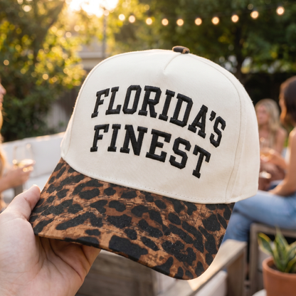 Close-up of a Florida’s Finest embroidered snapback hat featuring a cream crown and leopard print brim. Trendy Florida lifestyle cap with bold black embroidery, stylish animal print design, and casual coastal fashion appeal.