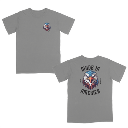 Grey patriotic graphic tee featuring a fierce bald eagle with an American flag bandana and bold “Made in America” gothic lettering, celebrating classic USA pride and heritage-inspired style.
