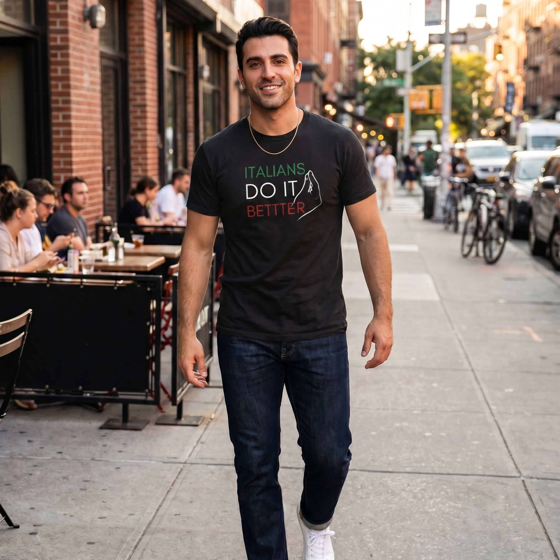 Man wearing a black “Italians Do It Better” graphic t-shirt featuring Italian flag colors while walking through a city street. Stylish Italian heritage shirt celebrating Italian pride, culture, family traditions, and casual everyday fashion.