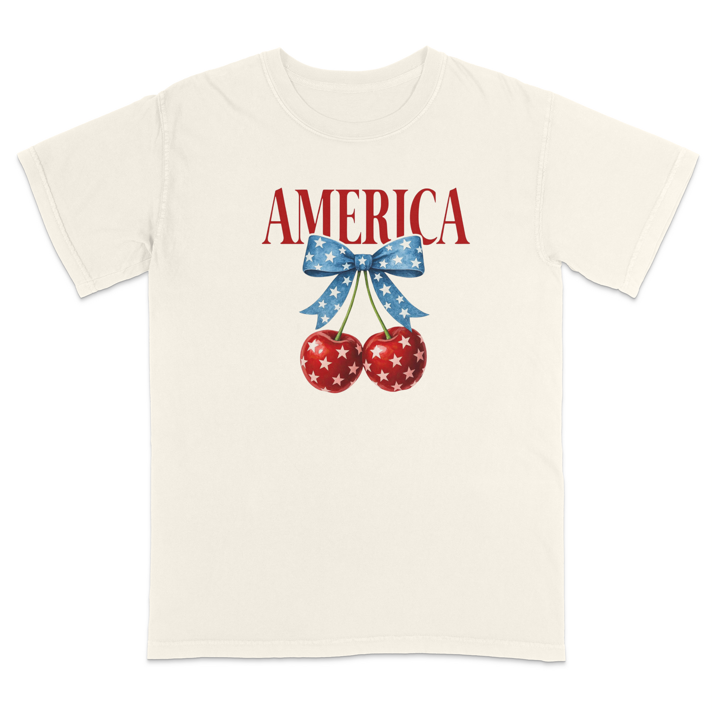 Ivory patriotic graphic t-shirt featuring red “AMERICA” text with star-pattern cherries and a blue bow design, combining vintage Americana style with playful patriotic fashion.