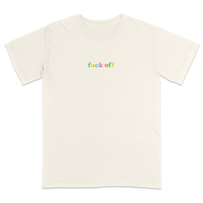Front view of a ivory T-shirt featuring the phrase "fuck off" in small lowercase letters across the chest. Each letter is embroidered in a different bright color, creating a subtle rainbow-inspired design with a minimalist aesthetic. A bold statement tee for adults with a sarcastic sense of humor, casual streetwear style, and colorful typography.