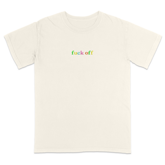 Front view of a ivory T-shirt featuring the phrase "fuck off" in small lowercase letters across the chest. Each letter is embroidered in a different bright color, creating a subtle rainbow-inspired design with a minimalist aesthetic. A bold statement tee for adults with a sarcastic sense of humor, casual streetwear style, and colorful typography.