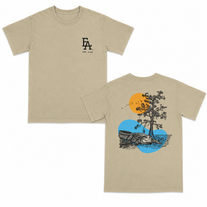 Khaki short-sleeve T-shirt with a minimalist black “FLA est. 2025” logo on the front and a detailed back graphic featuring a Florida alligator, tree, birds, and sun over water in a vintage outdoor illustration style.