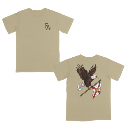 Khaki patriotic t-shirt featuring a small FLA® logo on the left chest and a large back graphic of a soaring bald eagle carrying the Florida state flag. Florida-inspired apparel combining state pride, American heritage, and outdoor lifestyle style. Perfect for patriotic events, fishing trips, hunting, boating, beach days, and everyday Florida living.