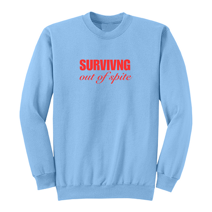 Front view of a light blue crewneck sweatshirt featuring the phrase "SURVIVING" in bold red block letters above the words "out of spite" in elegant red script centered on the chest. The clean, minimalist design stands out against the black fabric, creating a bold statement sweatshirt with a resilient and motivational aesthetic.