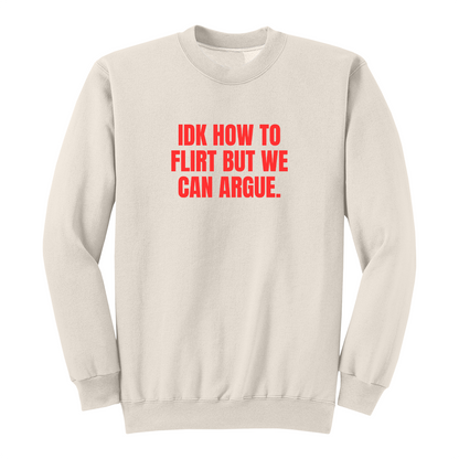 Front view of a natural long sleeve graphic crewneck featuring the bold red statement "IDK HOW TO FLIRT BUT WE CAN ARGUE." centered across the chest in large uppercase block lettering. This funny sarcastic long sleeve shirt combines relationship humor with bold typography, making it a casual streetwear piece for adults with a playful sense of humor.