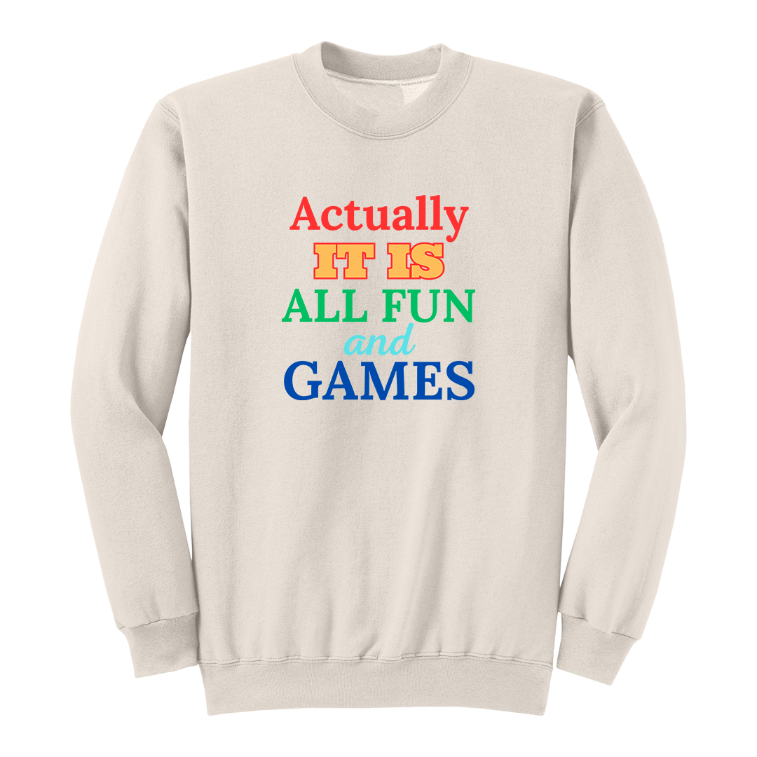 Front view of a natural long sleeve graphic T-shirt featuring the phrase "Actually IT IS ALL FUN and GAMES" in stacked multicolored typography. "Actually" is red, "IT IS" is gold with a red outline, "ALL FUN" is green, "and" is written in light blue script, and "GAMES" is bold blue. This playful retro-inspired graphic long sleeve shirt is perfect for casual wear, parties, game nights, and anyone with a fun sense of humor.