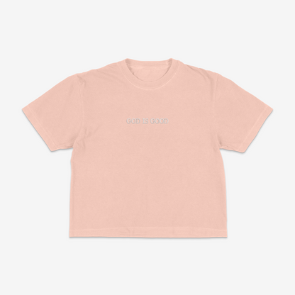 Peach boxy tee with 'GOD IS GOOD' text on a white background