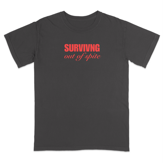 Front view of a pepper short sleeve t-shirt featuring the phrase "SURVIVING" in bold red block letters above the words "out of spite" in elegant red script centered on the chest. The minimalist red-on-black design creates a striking, resilient statement tee with a clean, modern aesthetic.