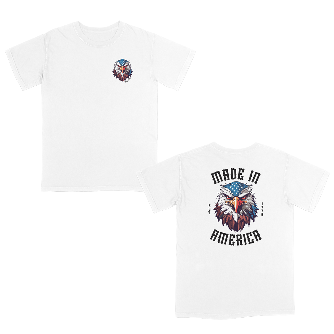 White patriotic graphic tee featuring a fierce bald eagle with an American flag bandana and bold “Made in America” gothic lettering, celebrating classic USA pride and heritage-inspired style.
