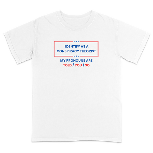 Front view of a white graphic T-shirt featuring the humorous phrase "I Identify as a Conspiracy Theorist" with "My Pronouns Are Told / You / So" printed below in bold patriotic red and blue lettering with stars and a bordered design. A funny political humor tee perfect for casual wear, parties, holidays, and anyone who enjoys satire and conspiracy-themed jokes.