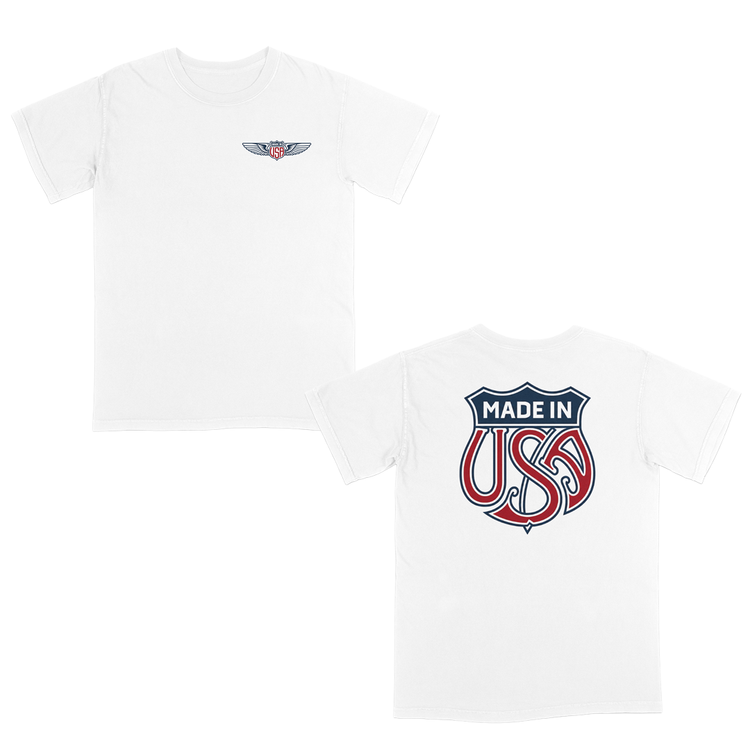 White patriotic graphic t-shirt with small USA wing logo on the front and oversized “Made in USA” graphic on the back in vintage red and blue Americana style.